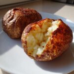 Two perfectly cooked air fryer baked potato halves showing a crispy skin and fluffy white interior.