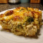 A close-up serving of creamy chicken broccoli rice casserole topped with bubbly, melted cheddar cheese.