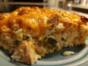 Close-up of a serving of chicken broccoli rice casserole with melted cheddar cheese topping.