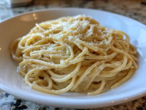 Close-up of creamy parmesan pasta tossed in sauce and topped with grated cheese.