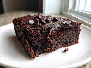 Close-up of a fudgy, rich dark chocolate sweet potato brownies slice topped with chocolate chips.