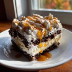 A square slice of rich gingerbread trifle layered with dark cake, cream, topped with whipped cream, caramel sauce, and cinnamon.