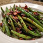 Close-up of glossy, bright green beans tossed with crispy bacon bits, highlighting the honey garlic glaze.