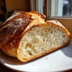 Close-up of a freshly baked Italian bread loaf, showing the open, airy crumb structure and golden crust.