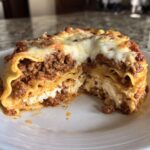 Cross-section of a rich slice of lasagna with cottage cheese, meat sauce, and melted cheese topping.