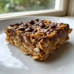 A square of delicious no-bake oatmeal bars, featuring visible oats and a chocolate chip topping.