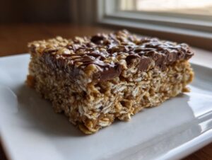A single square of rich, no-bake oatmeal bars topped with a thick layer of melted chocolate.