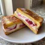 Two halves of golden brown stuffed french toast filled with cream cheese and strawberries.