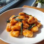 Close-up of pan-seared sweet potato gnocchi tossed in brown butter sauce and topped with crispy sage leaves.