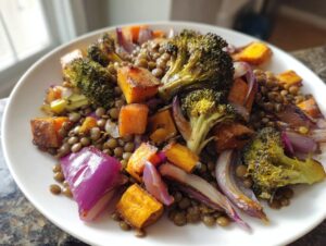 Close-up of a hearty veggie lentil salad featuring roasted broccoli, sweet potato cubes, and red onion over a bed of brown lentils.