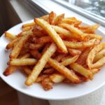 Close-up of perfectly golden and crispy air fryer french fries sprinkled generously with salt.