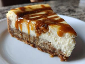 A close-up of a decadent slice of apple pie cheesecake topped with a rich caramel drizzle.