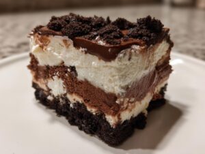 Close-up of a layered slice of Baileys Chocolate Cheesecake Trifle showing dark crust, chocolate mousse, and cream layers.