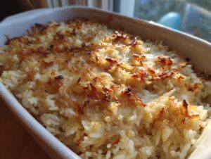 Close-up of baked french onion butter rice with a golden, crispy, browned top in a white casserole dish.