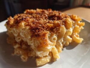 Close-up of a rich, creamy slice of baked mac and cheese featuring elbow macaroni and a golden-brown, crispy breadcrumb topping.