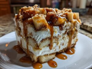 Close-up of a layered slice of caramel apple trifle featuring cream, cake layers, and a rich caramel drizzle over apple chunks.