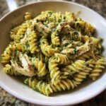 Close-up of creamy pesto pasta made with fusilli noodles and shredded chicken.