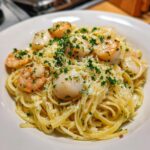 Close-up of creamy seafood pasta featuring linguine, seared scallops, shrimp, and fresh parsley.