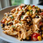 Close-up of creamy southwest chicken salad featuring shredded chicken, black beans, corn, and tomatoes.