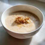 A close-up of a creamy bowl of roasted cauliflower soup garnished with roasted cauliflower florets.