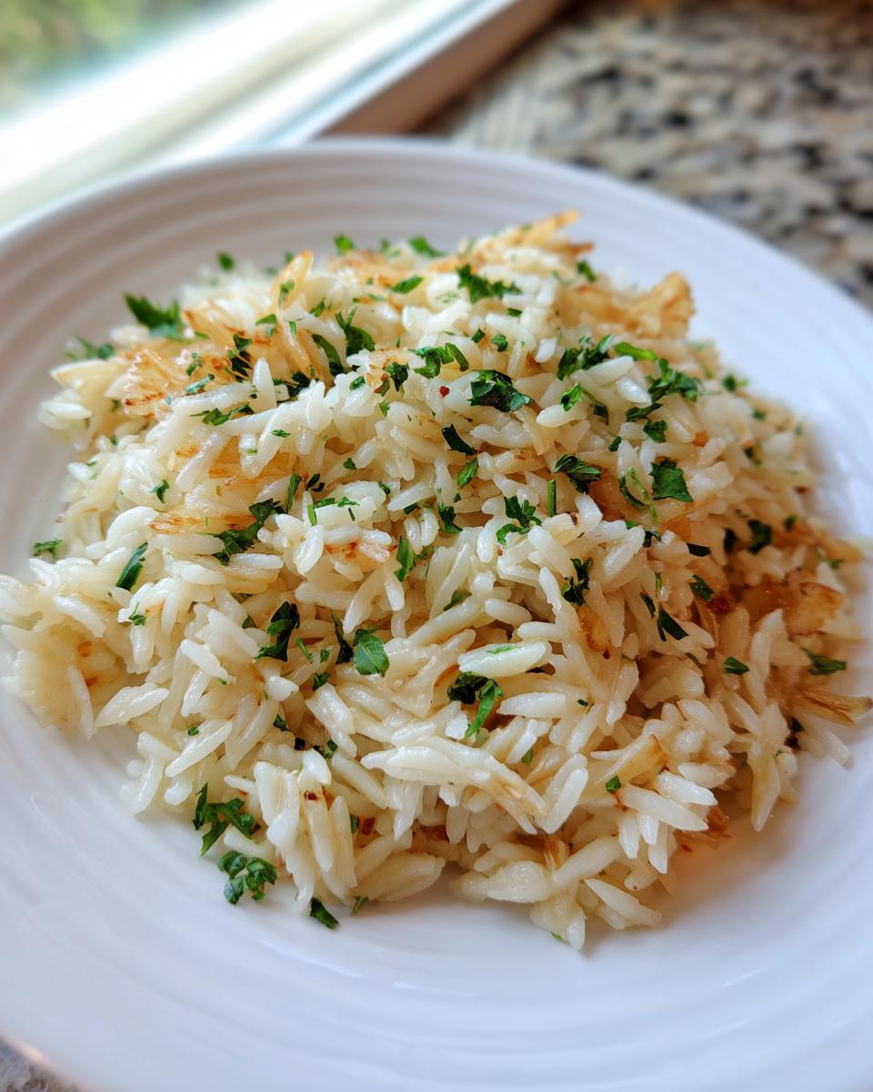 A close-up of fluffy, perfectly cooked rice pilaf garnished with fresh chopped parsley on a white plate.