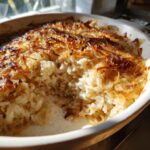 A close-up of baked french onion butter rice in a white dish, showing fluffy rice and a deeply caramelized onion topping.