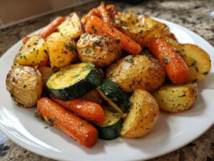 A close-up of perfectly roasted potatoes, carrots, and zucchini seasoned with herbs, showcasing the best Garlic Herb Roasted Veggies.
