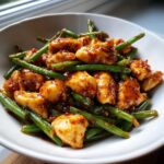 Close-up of bite-sized pieces of glazed chicken mixed with bright green beans, a perfect chicken and green beans dish.
