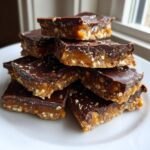 A stack of rich graham cracker toffee bars layered with caramel and topped with dark chocolate and sea salt.