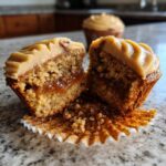 A pecan pie cupcakes cut in half showing the gooey caramel filling, topped with light brown frosting.