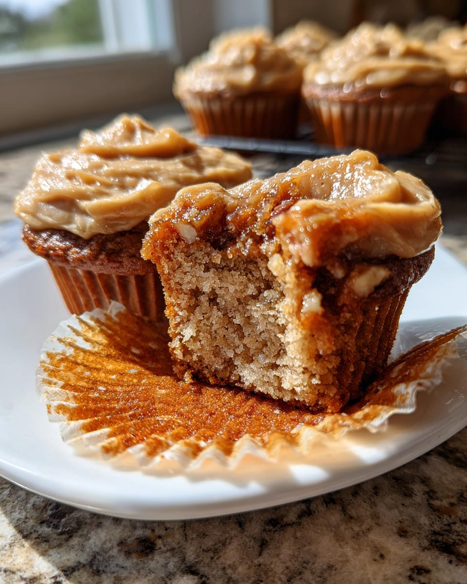 A close-up view of pecan pie cupcakes, one bitten into, showing the moist interior and thick caramel-colored frosting.