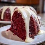 A close-up of a moist slice of red velvet bundt cake topped with thick, dripping white glaze.