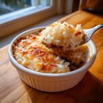 A fork lifts a bite of golden brown butter rice from a white ramekin, showing a cheesy or crusty top.