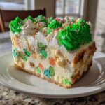 A close-up slice of christmas tree cheesecake featuring colorful cereal pieces embedded in a creamy filling, topped with green frosting trees and sprinkles.