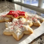Close-up of star-shaped sugar cookies decorated with white and red cookie icing and sprinkles.