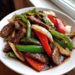 Close-up of tender beef strips mixed with bright green and red peppers and onions in a savory sauce, ready to eat pepper steak.