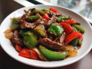 Close-up of Amazing 30-Minute pepper steak featuring tender beef strips, vibrant green and red bell peppers, and onions in a savory sauce.