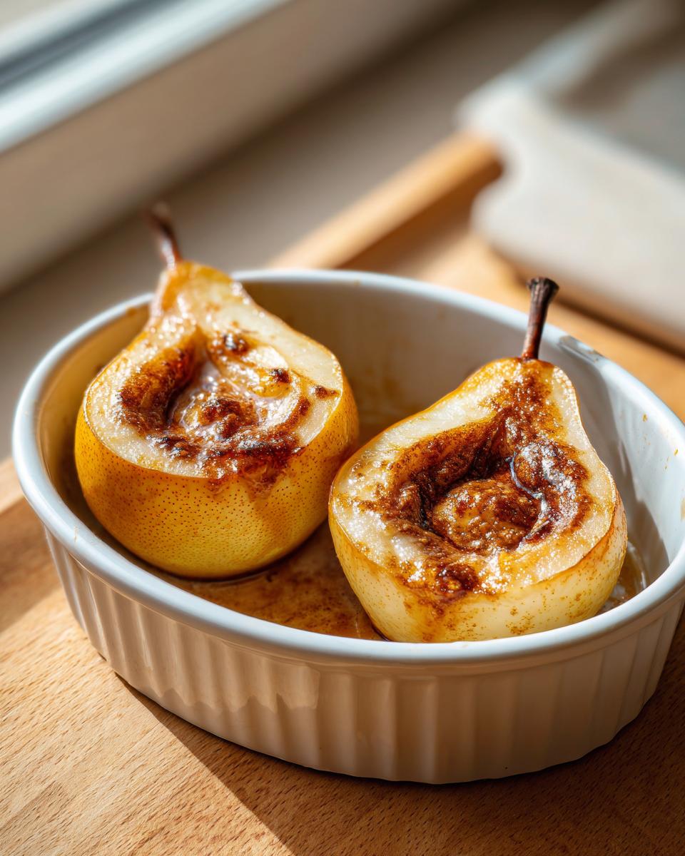 Close-up of two halves of caramelized baked pears with cinnamon filling in a white ramekin.