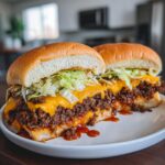 Two halves of big mac sloppy joes piled high with meat, melted cheese, and shredded lettuce on buns.