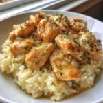 Close-up of tender chicken scampi pieces served over creamy garlic parmesan rice, garnished with parsley.