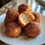 A stack of golden brown cinnamon sugar snowball cookies, one broken open to show the soft interior.