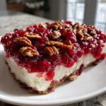 A close-up of a serving of cranberry cream cheese dip topped with cranberry sauce and pecans.
