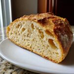 Close-up of a thick slice of crusty italian bread showing an open, airy crumb structure.