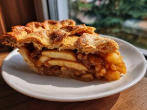 Close-up of a perfect slice of homemade apple pie showing thick apple filling and flaky, golden crust.
