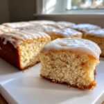 A close-up of a soft maple donut bar slice showing the fluffy interior and thick white glaze topping.