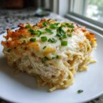 A square serving of creamy monterey chicken spaghetti topped with melted, browned cheese and fresh chives.