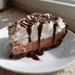 A decadent slice of no-bake Mississippi Mud Pie with chocolate filling, whipped cream, and chocolate sauce.