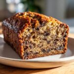 Close-up of a moist slice of chocolate chip protein banana bread with a dark, caramelized crust.