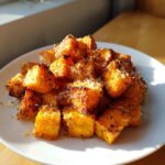 A pile of perfectly roasted, cubed sweet potatoes seasoned and topped with grated cheese.