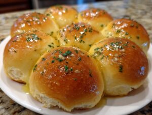 A cluster of soft, golden brown buttery rolls glistening with melted butter, garlic, and chopped parsley.